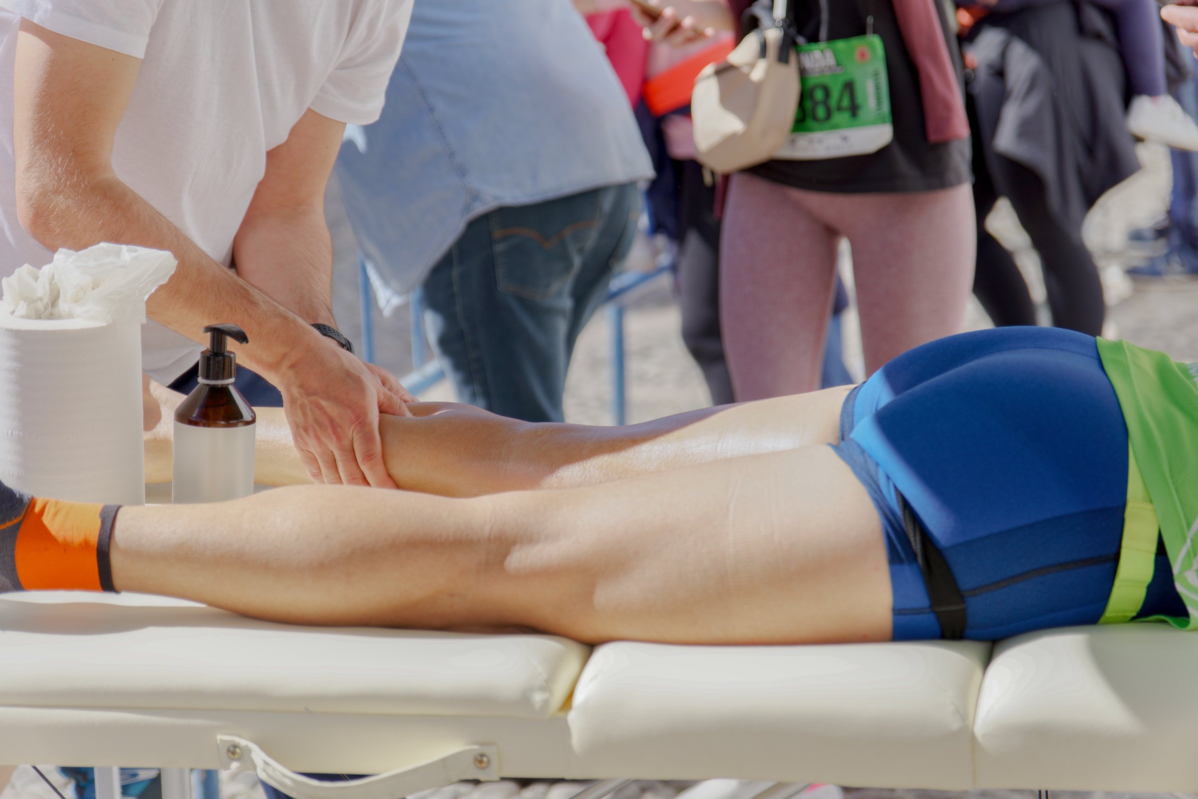 Athletic Trainer Assisting a Runner With Leg Massage at a Marathon Event